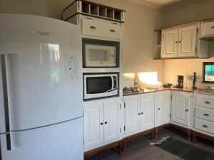 a kitchen with white cabinets and a white refrigerator at Bortolotti Residence in Penha