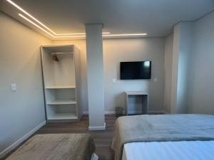 a bedroom with a bed and a tv on a wall at Bortolotti Residence in Penha