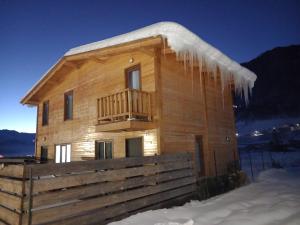 a wooden house with icicles hanging from it in the snow at Cottage Qel in Mestia