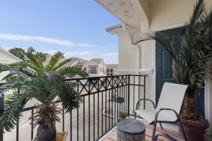 a balcony with a white chair and a palm tree at Seaside Comfort in Gulfport