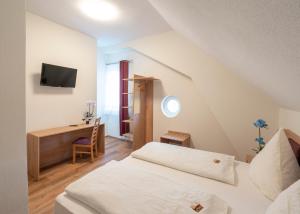 a bedroom with a bed and a desk with a television at Hotel Restaurant Schwert in Kehl am Rhein