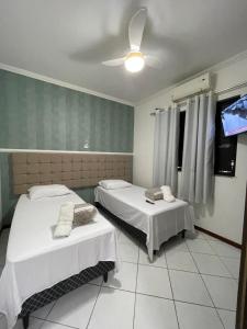 a room with two beds and a flat screen tv at Apto Conquista Imóveis exclusivo para Booking in Vitória da Conquista