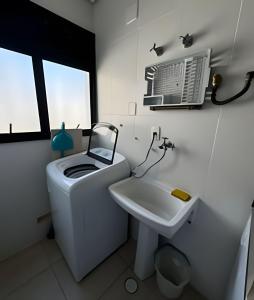 a bathroom with a toilet and a sink and a fan at Paraíso com piscina: Pitangueiras Lazer Completo in Guarujá