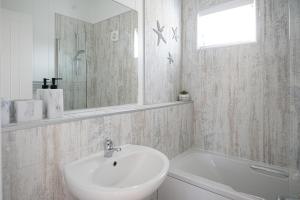 a bathroom with a sink and a mirror and a tub at Galwad y Mor in Llanfairpwllgwyngyll +43 photos