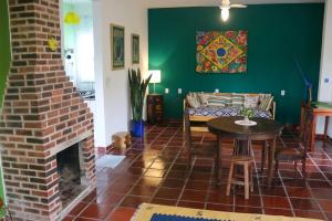 a living room with a brick fireplace and a table at Sobrado da Casa Azul - Penedo in Itatiaia