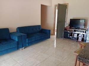 a living room with two blue couches and a tv at Cantinho da Paz in Capela do Alto