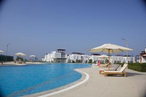 a pool with chairs and umbrellas next to some buildings at Casa de Playa - Asia - SELENE beach house in Asia