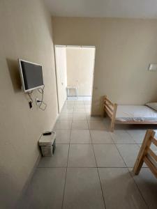 a room with a bed and a tv on a wall at Alojamento Obracamp in Campinas