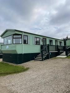a green mobile home with a porch and stairs at Pet Friendly Caravan - Slaley Forest - Sleeps 4 in Hexham