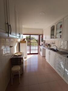 una cucina con mobili bianchi, un lavello e un frigorifero di GREEN GARDEN APARTMENT IN ODIVELAS a Odivelas