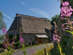 an old stone building with a thatch roof at Le "Refuge" douillet, chaleureux, massages bien-être in Saint-Front