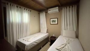 a bedroom with two beds and a window with curtains at Pousada Recreio Casa Grande in Cascavel +29 photos
