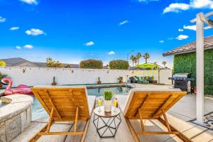 eine Terrasse mit zwei Stühlen und einem Pool in der Unterkunft Amazing 5BR Villa with Heated Pool in Bermuda Dunes + 47 Fotos