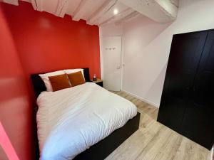 una camera da letto con una parete rossa e un letto di l'Hibiscus a Rouen