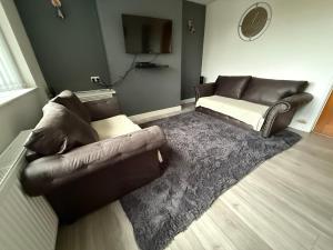 a living room with a leather couch and a rug at Cosy, Modern Home Near BHX, NEC and City Centre in Birmingham