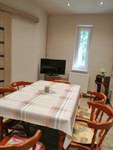 a dining room with a table with chairs and a television at Új Lilla Apartman in Keszthely