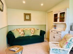 un salon avec un canapé vert et une table dans l'établissement Wattle Creek Cottage with Breakfast Basket, à Amberley