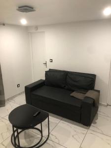 a black couch and a table in a room at Cozy and well located apartment in Tremblay En France