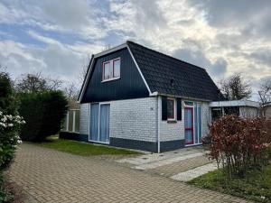 une petite maison avec un toit noir et des fenêtres rouges dans l'établissement Holiday bungalow with wifi near beach, à Sint Maartenszee