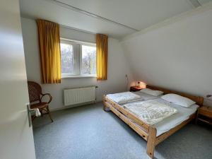 une chambre avec un lit, une chaise et une fenêtre dans l'établissement Holiday bungalow with wifi near beach, à Sint Maartenszee