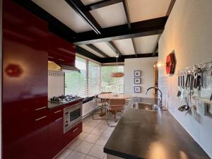 a kitchen with red cabinets and a table in it at Bungalow for 4 people in Wildrijk in Sint Maartenszee