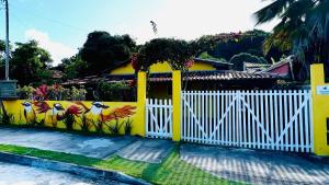 a yellow fence with chickens painted on it at Casa Bem-te-vi - Passarim Hospedagem in Cumuruxatiba