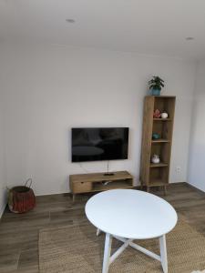sala de estar con mesa blanca y TV en Escolar, en Cedeira