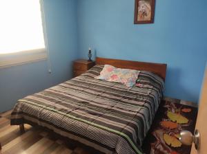 Una cama en un dormitorio con una pared azul. en Alojamiento Miguel y Lily, en El Tabo