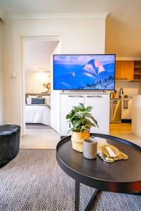 a living room with a table and a large screen tv at Bright 1BR with On-Site Gym I Sauna I Pool and Parking in Sydney +36 photos