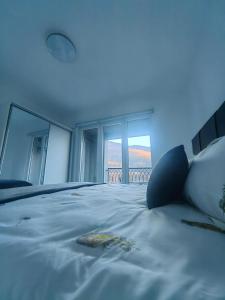 a bedroom with a large white bed with windows at Apartman Nermin in Travnik