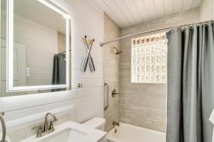 a white bathroom with a sink and a mirror at 5 Mi to Dtwn Bright Home with Yard in Pensacola! in Pensacola +16 photos