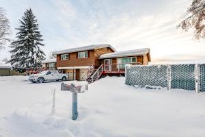una casa de madera con un coche en la nieve en Riverside Retreat Cozy Fairbanks Home with View, en Fairbanks
