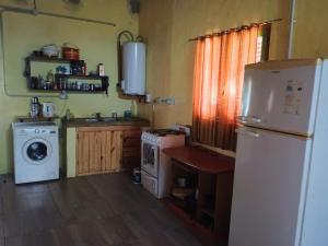 a kitchen with a refrigerator and a washer and dryer at Ñanderoga in San Marcos Sierras
