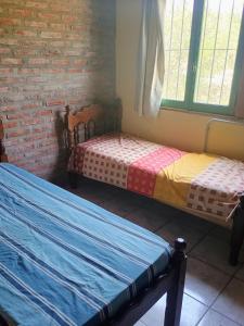 two beds in a room with a brick wall at Ñanderoga in San Marcos Sierras