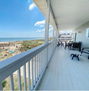 a porch with benches and tables on the beach at Sojourn The Lighthouse Beach Front Resort Villa in North Camellia Acres