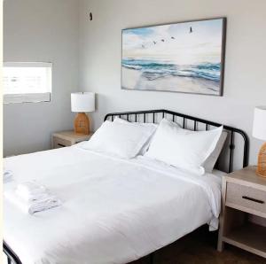 a bedroom with a white bed with birds on the wall at Sojourn The Lighthouse Beach Front Resort Villa in North Camellia Acres