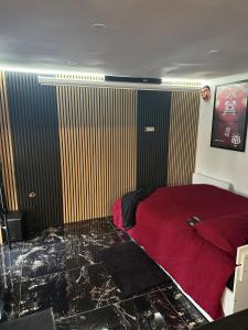 a bedroom with a red bed and a screen at Cabanon aux films in Saint-Brieuc