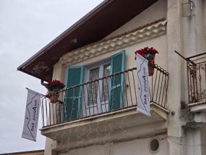 a building with green shutters and flowers on a balcony at postAielli - Arte, Natura e Relax in Aielli
