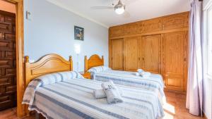two beds in a room with wooden cabinets at Gonzalez Almuñécar by Ruralidays in Almuñécar +18 photos