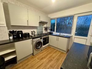 a kitchen with white cabinets and a washer and dryer at FERRY HOUSE - INVOICE and REDUCED PRICE only via SUNRISE SHORT LETS DUNDEE, 4 Bed House, Great for Contractors, Fully Equipped, Private Parking, Easy Ring Road Access - ASK SUNRISE SHORT LETS - LONG TERM RATES AVAILABLE in Dundee