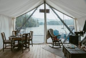 a tent with a table and chairs and a view of the water at Lux Remote Glamping Hideaway in Ucluelet