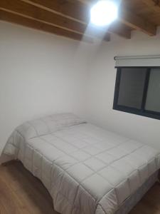 a white bed in a room with a window at Alto del pinar in Mar Azul +16 photos