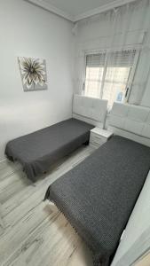 ein Schlafzimmer mit zwei Betten und einem Fenster in der Unterkunft Playa del Cura apartment with 2 bedrooms in Torrevieja