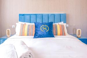 a bed with a blue headboard and pillows at Gold Coast Photography Inn in Estoril