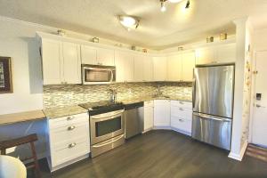 a kitchen with white cabinets and a stainless steel refrigerator at Seaside Escape in Fort Pierce +14 photos
