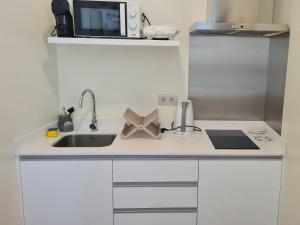 a small kitchen with a sink and a microwave at Casa Linda Baía in Porto da Cruz