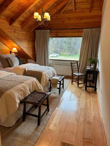 a bedroom with two beds and a large window at El Pedregoso Flights & Lodge in Cholila