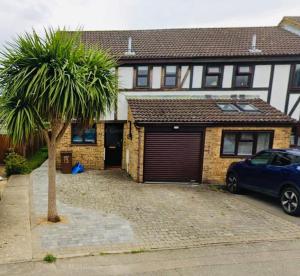 a car parked in front of a house with a palm tree at Gillingham Home with garage in Rainham