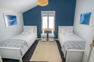 two beds in a room with blue walls at Midd's on the Beach - luxury beach front apartment in Albany