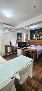 a room with two beds and a table and a desk at Flat S4 Hotel - Águas Claras - Brasília in Brasilia